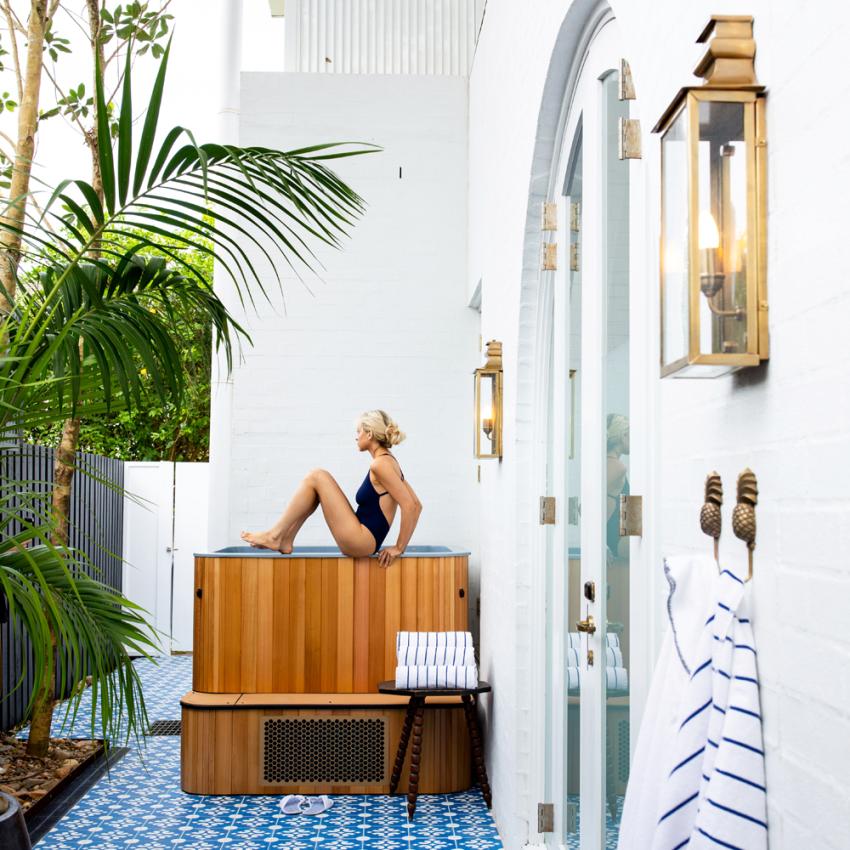 Women sitting on top of the cold plunge at Halcyon Wellness